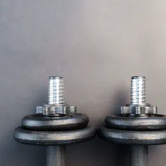 A pair of black iron dumbbells against a gray background