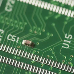 Close-up of a green circuit board with silver solder joints, copper traces, and surface-mounted components